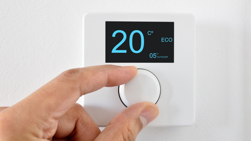A person changing a thermostat