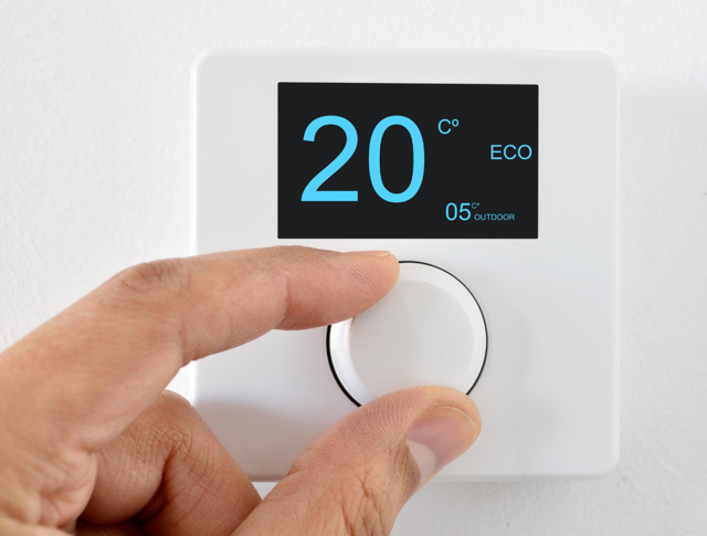 A person changing a thermostat