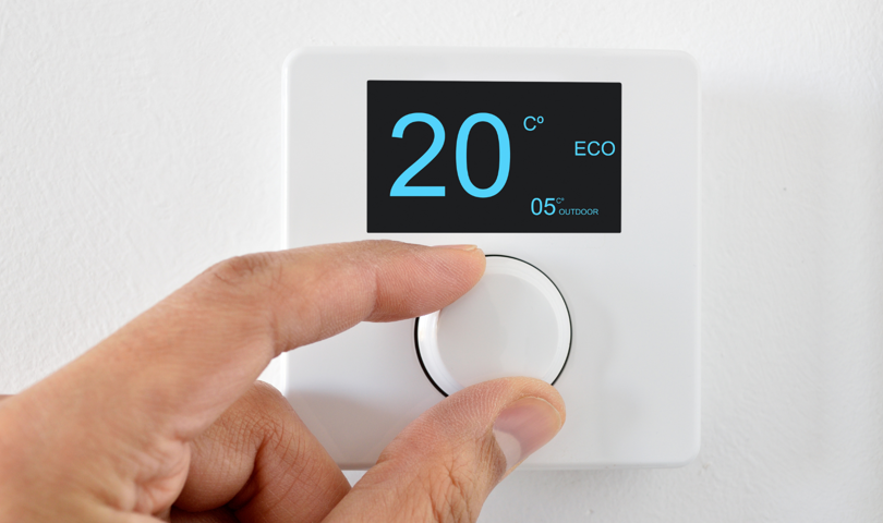 A person changing a thermostat