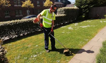 Grounds Maintenance Contractor Trimming The Grass On A Sunny Day