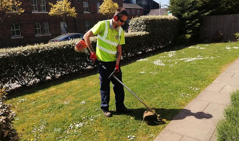 Grounds Maintenance Contractor Trimming The Grass On A Sunny Day