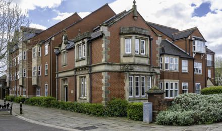 Exterior View Of A Building On A Cloudy Day, Featuring Traditional Architecture With Red Brick And Stone Accents