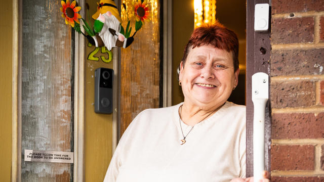 Tenant Standing In Her Doorway Smiling With A Yellow Door
