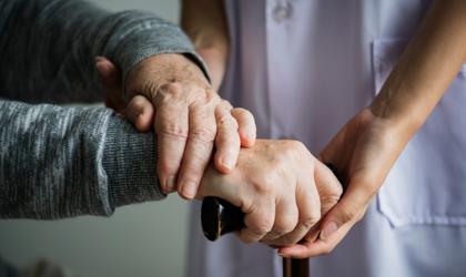 Closeup Shot Of Hands Of A Carer Supporting Elderly Person To Use A Walking Stick