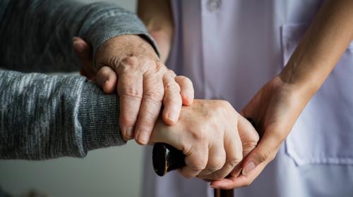 Closeup Shot Of Hands Of A Carer Supporting Elderly Person To Use A Walking Stick