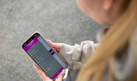 A Person Looking At Their Phone With The Midland Heart App Opened