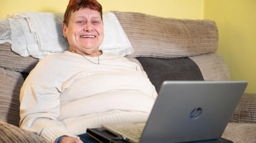 Person Smiling While Using A Dell Laptop On A Couch