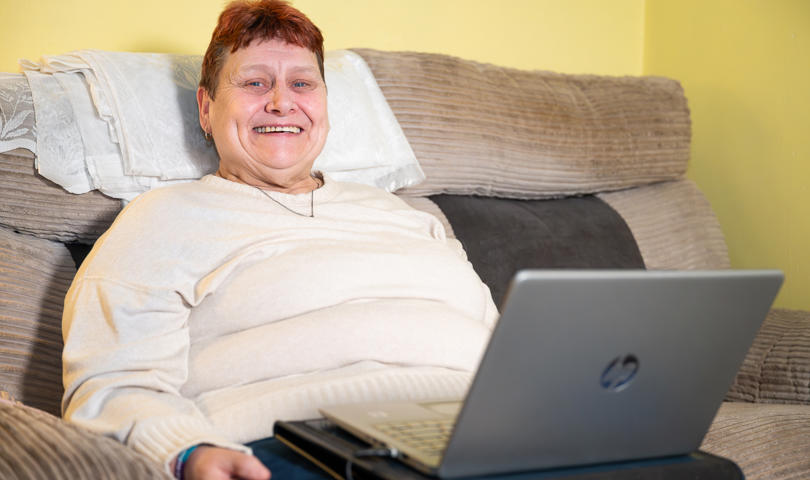 Person Smiling While Using A Dell Laptop On A Couch