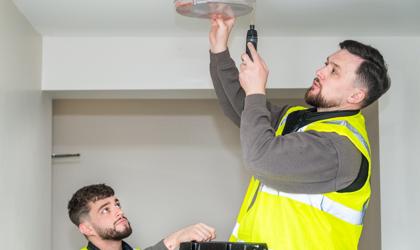 Two Repairs Operatives Fixing A Light For A Tenant