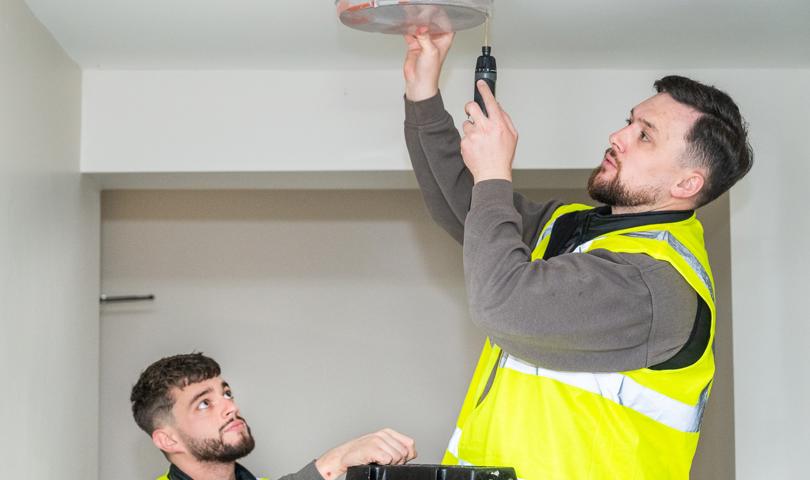 Two Repairs Operatives Fixing A Light For A Tenant