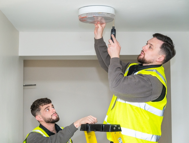 Two Repairs Operatives Fixing A Light For A Tenant