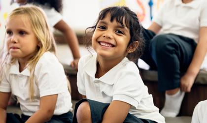 Happy Kid Smiling At The Camera In Uniform In A Classroom Setting (1)