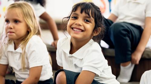 Happy Kid Smiling At The Camera In Uniform In A Classroom Setting (1)