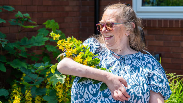 Tenant Holding Flowers In The Sunshine