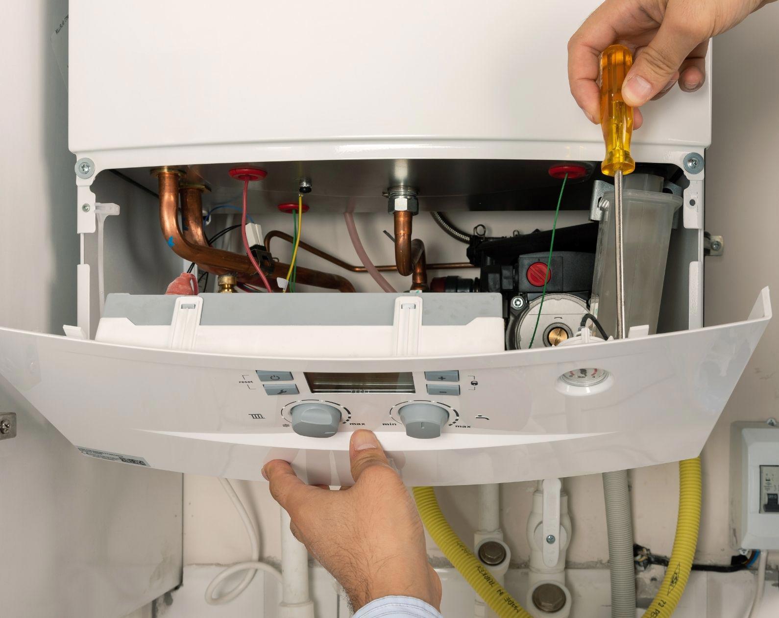A person opening up the boiler with a screwdriver A person opening up the boiler with a screwdriver