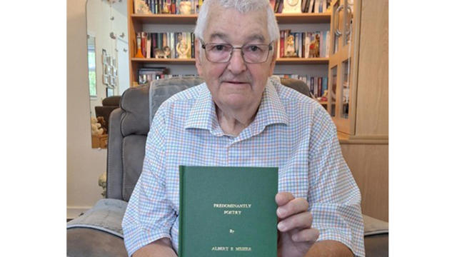 Man Holding A Book To Camera Titled Predominantly Poetry