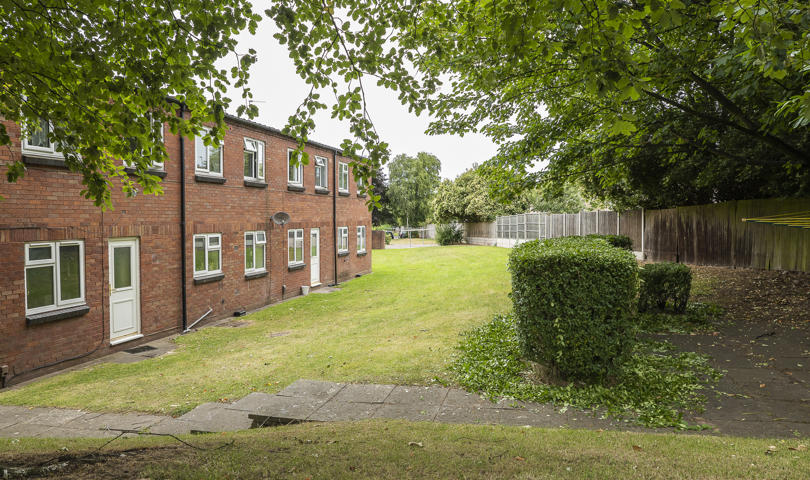A row of homes on the left with fencing and greenery on the right