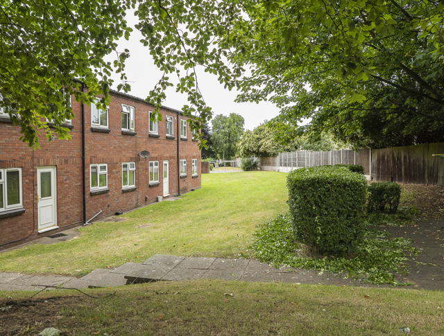 A row of homes on the left with fencing and greenery on the right