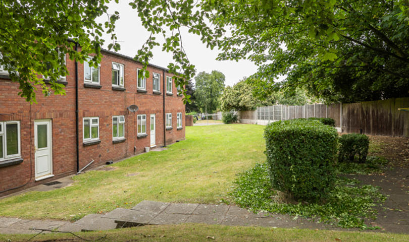 A row of homes on the left with fencing and greenery on the right