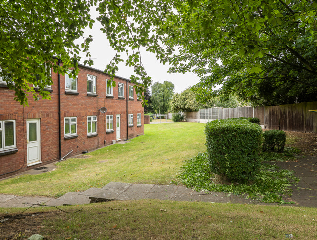 A row of homes on the left with fencing and greenery on the right