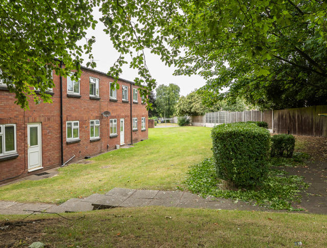 A row of homes on the left with fencing and greenery on the right