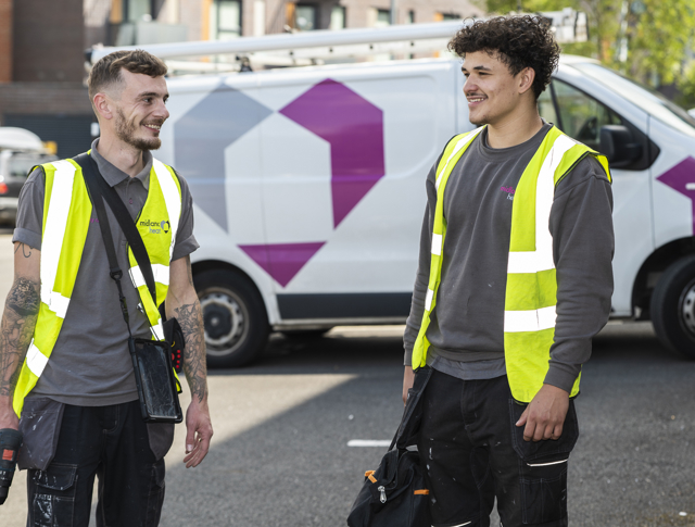 Electrician and an apprentice smiling in a car park