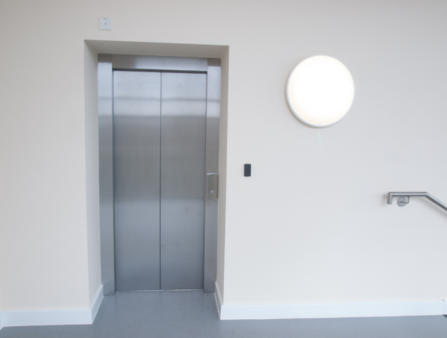 A lift with a circular wall light to the right