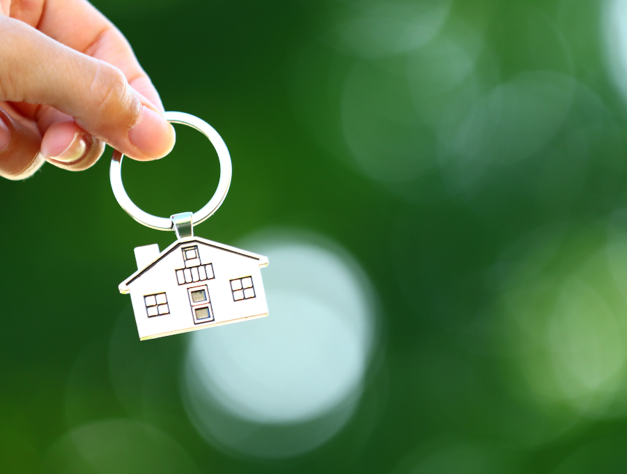 A hand holding a keyring in the shape of a house