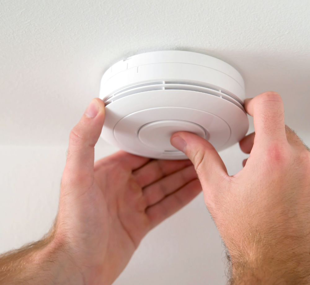 Person pushing the button of a smoke alarm