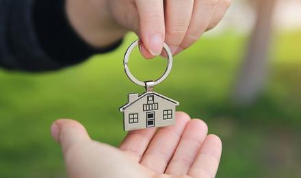 A keyring which is a house being passed from one hand to another