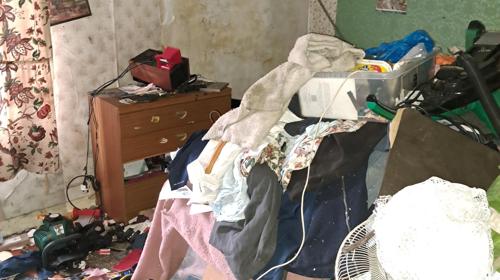 Cluttered Room With Piles Of Clothing, Household Items And Belongings Stacked Across The Floor