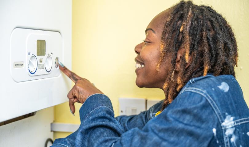 Woman Wearing Blue Jacket Adjusting Boiler Controls