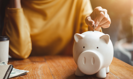 A person putting a coin in a piggy bank