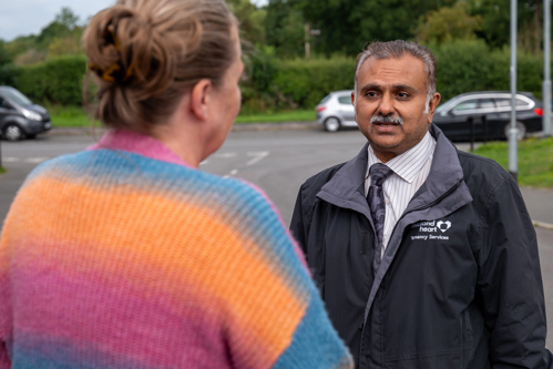 A Midland Heart employee, holding a clipboard and talking to 2 tenants