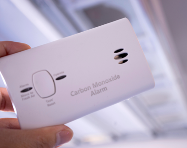 Image shows someone holding a carbon monoxide alarm