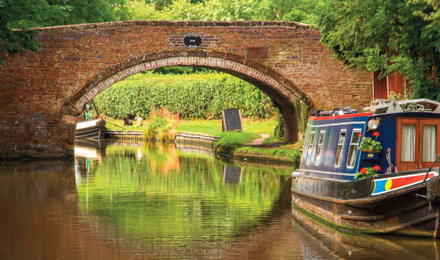 A canal with a bridge and a barge in The Black Country