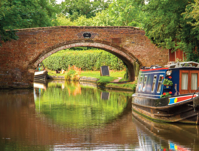 A canal with a bridge and a barge in The Black Country