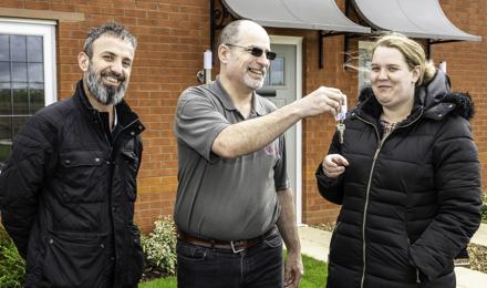 A tenant receiving the new key to their home from a Midland Heart employee