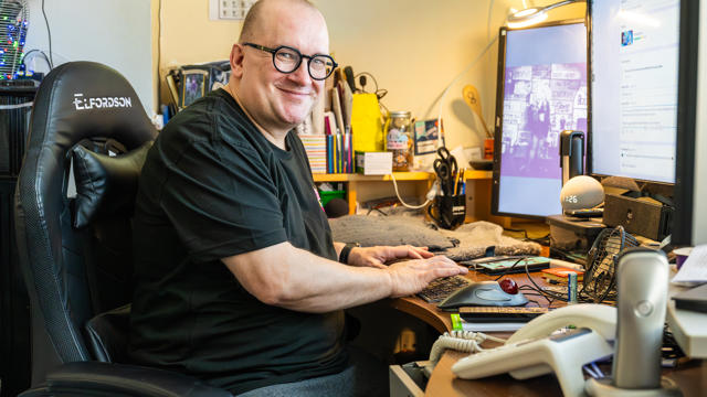 A Man Sitting At His Desktop Computer Smiling