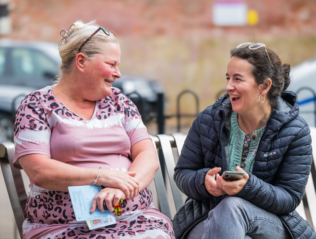 2 women sitting on a bench laughing