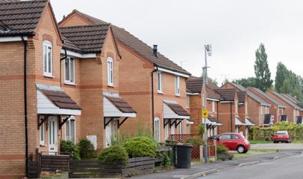 A Row Of Homes With A Red Car In The Background