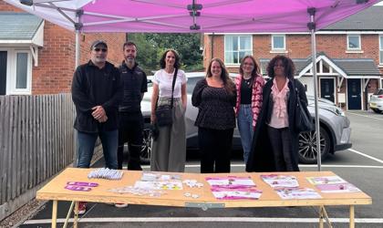 Group Of People Stood Smiling In Front Of A Table At An Event Under A Gazebo