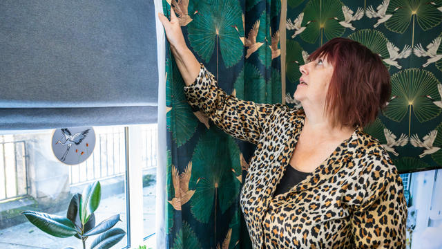 Tenant With A Leopard Print Shirt Closing Her Curtains