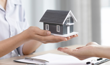 A person holding a miniature home to symbolise selling your home