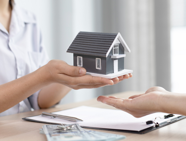 A person holding a miniature home to symbolise selling your home