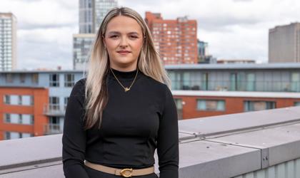 Woman Stood On A Rooftop Terrace In A Black Top With Shoulder Length Hair