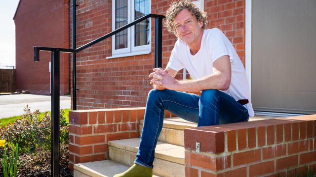 A Man Sitting On A Step Outside His Home