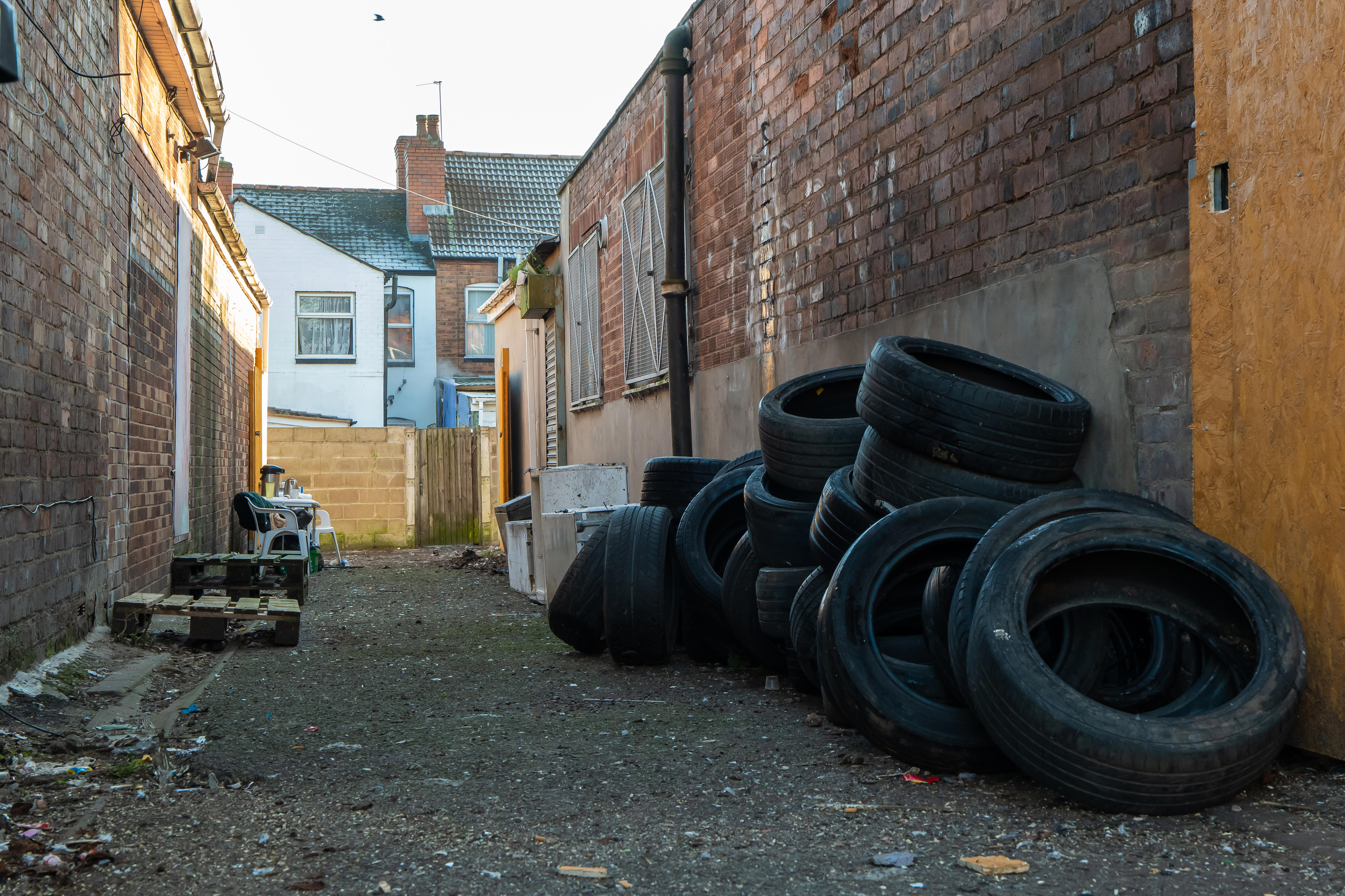 Narrow Street With Stacked Old Tires Against A Brick Wall