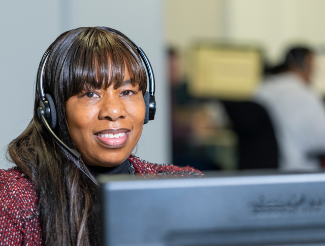 A Midland Heart employee wearing a headset at their desk and computer