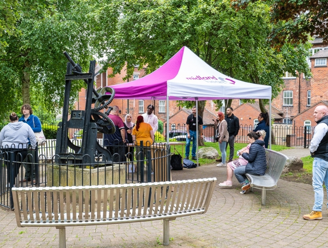 Group Of People Gathered Around A Purple Midland Heart Tent In A Park